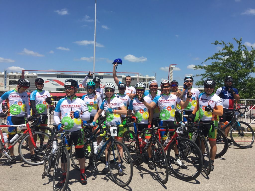 Group of Enerflex cyclists gather with bikes, wearing matching jerseys, ready for a ride to support MS 150 on a sunny day.