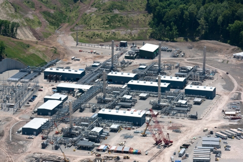 Aerial view of an industrial natural gas processing plant surrounded by greenery and construction equipment.