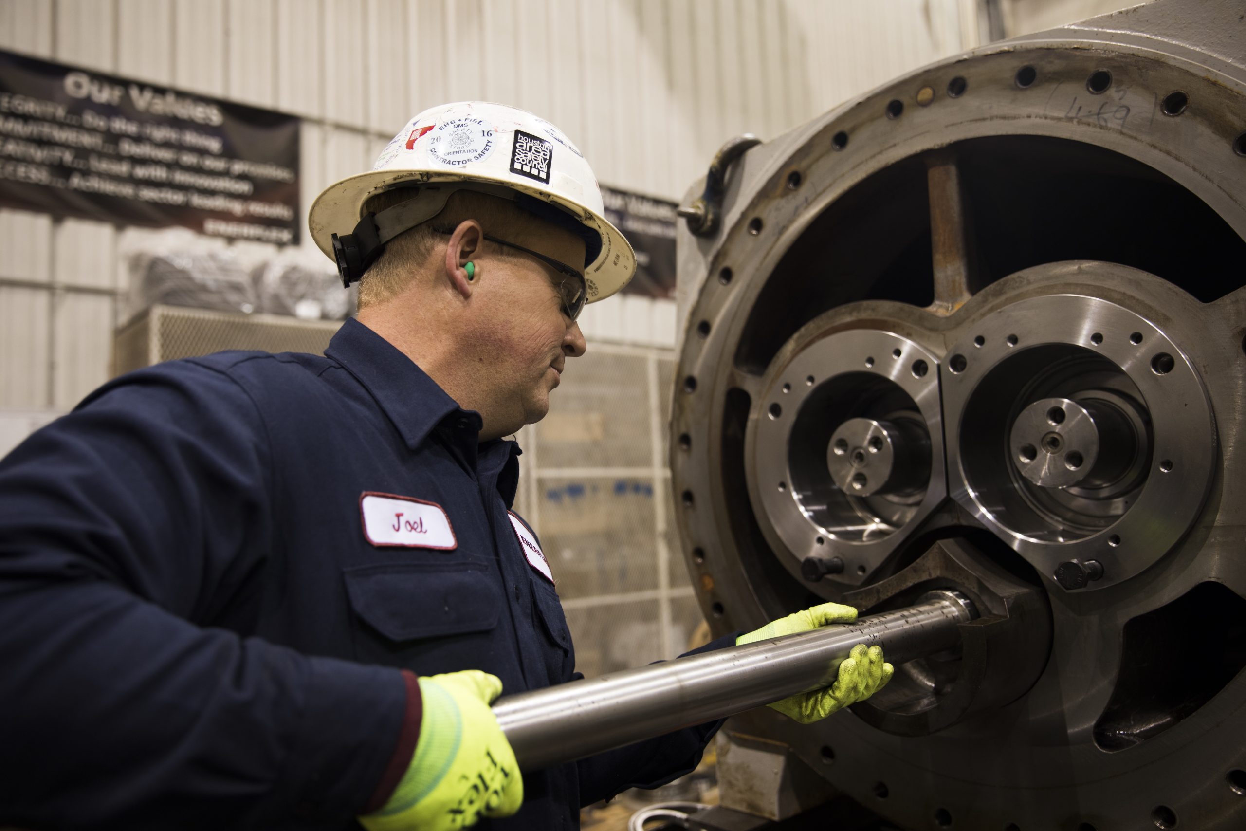 Factory worker in safety gear operating heavy machinery in an industrial setting.