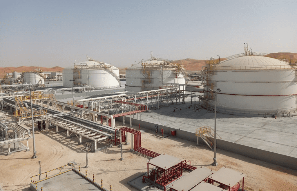 Industrial tanks and pipelines in a desert-based gas plant, showcasing large storage tanks and infrastructure.