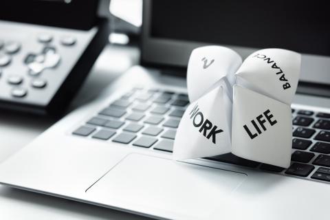 Origami fortune teller on a laptop keyboard with words: work, life, and balance, emphasizing work-life balance concept.