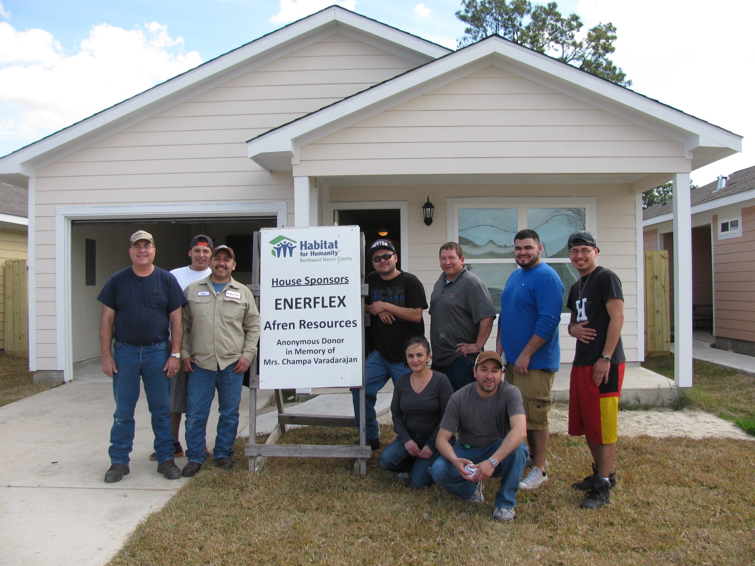 Volunteers standing in front of a newly built house sponsored by Enerflex and Afren Resources for Habitat for Humanity.