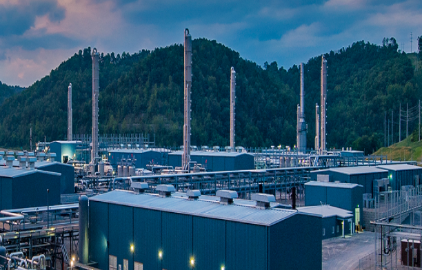 An Enerflex facility at sunrise with mountains and clouds in the background.