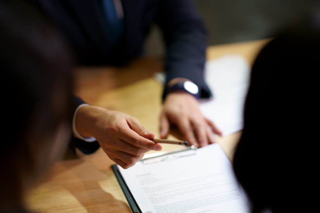 A close-up image of someone being offered a pen and a document to sign.