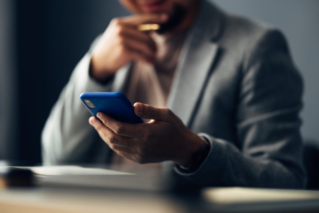 A person in a business suit contemplating a smartphone